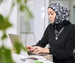 female-muslim-designer-working-on-laptop-in-kitche-2022-03-16-00-34-52-utc